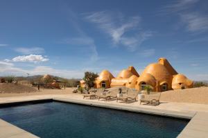 a resort with a swimming pool in front of a building at Sandora Domes - Architectural Retreat Near National Park in Joshua Tree