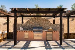 a patio with an outdoor kitchen in front of a stone wall at Sandora Domes - Architectural Retreat Near National Park in Joshua Tree