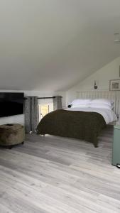 a white bedroom with a large bed and a tv at The Loft in Gwys Station
