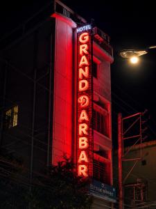 a hotel sign is lit up in red at night at Hotel Grand Darbar in Barisāl