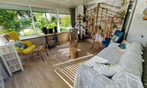 a living room with a couch and chairs and windows at Gîte La Pequelette in Saint-Ambroix