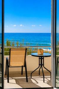 a table and a chair on a balcony with the ocean at Sole e Mare B2 Beachfront Sea View Apartment in Koutsourás +9 photos