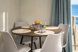 a table with chairs and a bowl of fruit on it at Sole e Mare B2 Beachfront Sea View Apartment in Koutsourás
