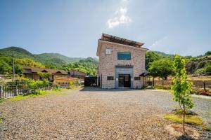 a building on a gravel road next to a fence at Okcheon Somakdaegi Pension in Okcheon