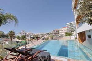 a swimming pool with chairs next to a building at Ilio Boutique Hotel in Ksamil