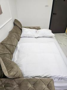 ein Bett mit weißen Laken und Kissen in einem Zimmer in der Unterkunft Studio centar Lazic 2 in Šid