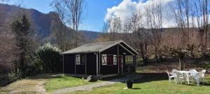 a small black shed with a table and chairs at LES CHALETS de MONTORGUEIL in Saurat
