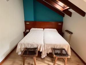 ein Schlafzimmer mit einem weißen Bett und zwei Stühlen in der Unterkunft Hotel Torrepalacio in Proaza