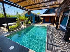 a swimming pool in a backyard with a pergola at Baannaisuk Pool Villa in Ban Mae Pu Kha