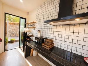 a kitchen with black and white tiled walls at Baannaisuk Pool Villa in Ban Mae Pu Kha