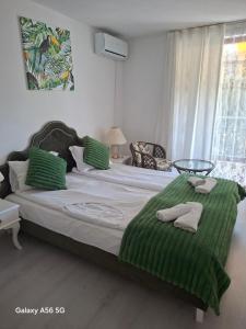 a large bed with green sheets and pillows on it at хотел Кристиан in Sozopol