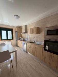 a kitchen with wooden cabinets and a table and a sink at PortoHome 2 in Portomarin