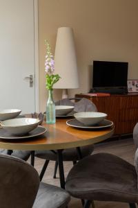a table with plates and a vase with flowers on it at Het Bakkershuus in Gramsbergen