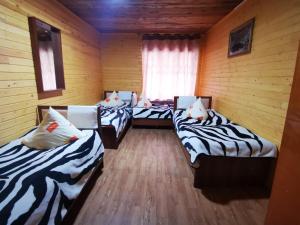 three beds in a room with wooden walls at Artuch Camp - Fan Mountains in Yakkakhona
