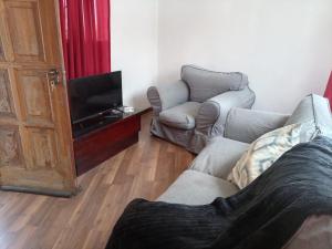 a living room with two chairs and a television at Stay with Tayo in Kempton Park