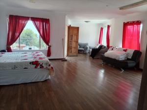 a bedroom with a bed and a living room with red curtains at Stay with Tayo in Kempton Park
