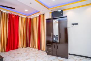 a room with red and yellow curtains and a television at RR complex in Trincomalee