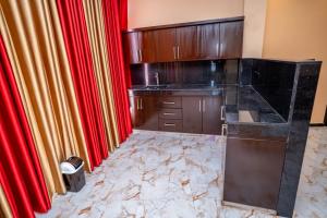 a kitchen with wooden cabinets and red curtains at RR complex in Trincomalee