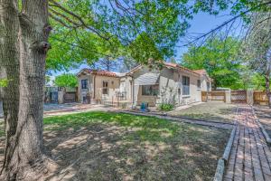 a white house with a tree in the yard at Highly Walkable Area! Charming Roswell Bungalow in Roswell