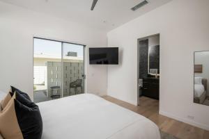 a white bedroom with a bed and a tv at Mercury @ Elemento49 - Pool Spa - Sleeps 16 in Indio +44 photos