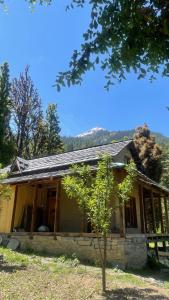 a house with glass doors and a tree at Mansa Homestay in Kalgha