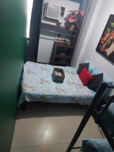 a small bedroom with a bed with a suitcase on it at Ortigas Uptown Bonifacio CBD Hostel in Sampong