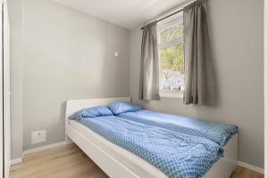 a bedroom with a bed with a blue comforter and a window at Home and Away in Vaksdal