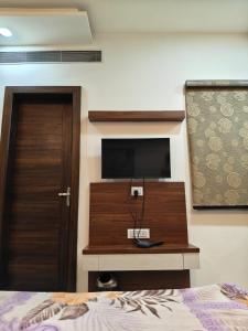 a bedroom with a bed and a television on a wall at Crown Palace Hotel & Restaurant in Hāpur