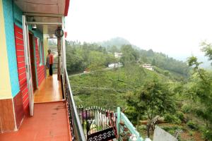 a man standing on a balcony looking at a hill at Sunshine retreat in Coonoor +10 photos