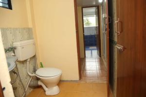a bathroom with a toilet and a door to a hallway at Sunshine retreat in Coonoor