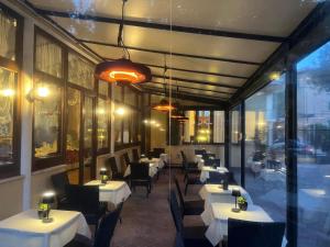 ein Restaurant mit weißen Tischen und Stühlen und Fenstern in der Unterkunft Hotel Villa Edera in Lido di Venezia