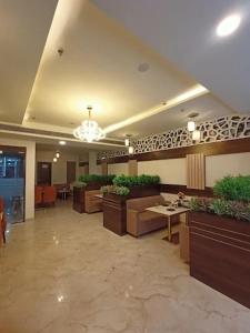 a lobby with tables and potted plants in a building at Crown Palace Hotel & Restaurant in Hāpur