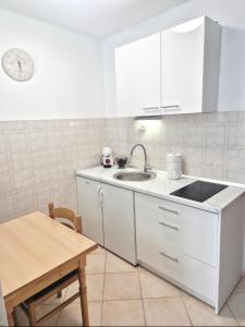 a white kitchen with a sink and a table at Apartments Mate in Komiža