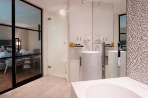 a bathroom with white walls and a large mirror at Van der Valk Hotel Hollands Kroon in Wieringerwerf +44 photos