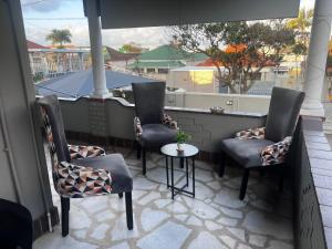 a balcony with three chairs and a small table at Peaceful Accommodation in Durban