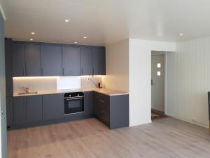 an empty kitchen with black cabinets and a sink at Evjen H0101 in Tromsø