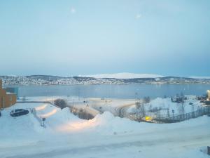 a beach covered in snow next to a body of water at Evjen H0101 in Tromsø