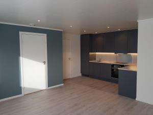 an empty kitchen with black cabinets and a white door at Evjen H0101 in Tromsø +4 photos