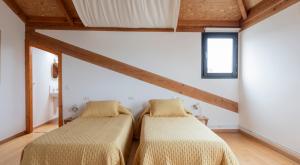 two beds in a room with white walls and wooden ceilings at NAMOR - Buhardilla Zen in Ribadeo