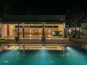 a swimming pool in front of a house at night at Myla Lodge in Anuradhapura