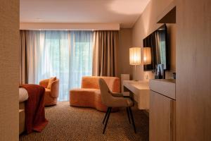 a hotel room with a desk and a bedroom at Van der Valk Hotel Hollands Kroon in Wieringerwerf