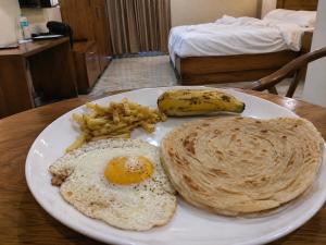 a plate of food with eggs and a banana and french fries at Hotel Grand Darbar in Barisāl