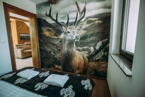 a painting of a deer on a wall next to a bed at Apartament CEKO 2 in Ostrowsko