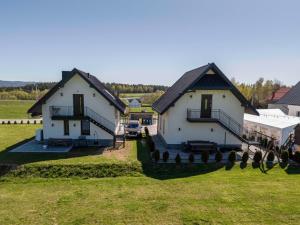 two white houses with black roofs in a field at Apartament CEKO 2 in Ostrowsko