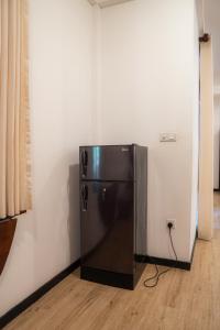 a black refrigerator in a corner of a room at Diana Residence in Matara