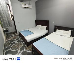 two beds in a small room withthritisthritislictslictslicts at Al Qadir Residence in Multan