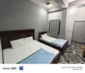 a hotel room with two beds and a mirror at Al Qadir Residence in Multan +16 photos