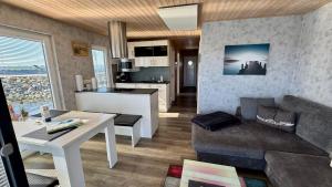 a living room and kitchen with a couch and a table at Hausboot Fehmarn in Fehmarn