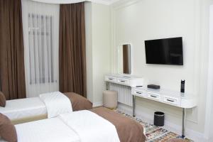 a hotel room with two beds and a flat screen tv at Veranda XF Hotel in Samarkand