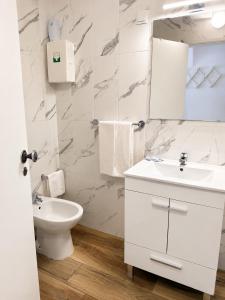 a white bathroom with a sink and a toilet at Apartamentos Central in Quarteira +13 photos